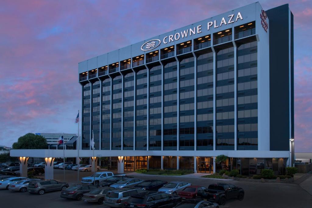 a building with cars parked in a parking lot at Crowne Plaza San Antonio Airport by IHG in San Antonio