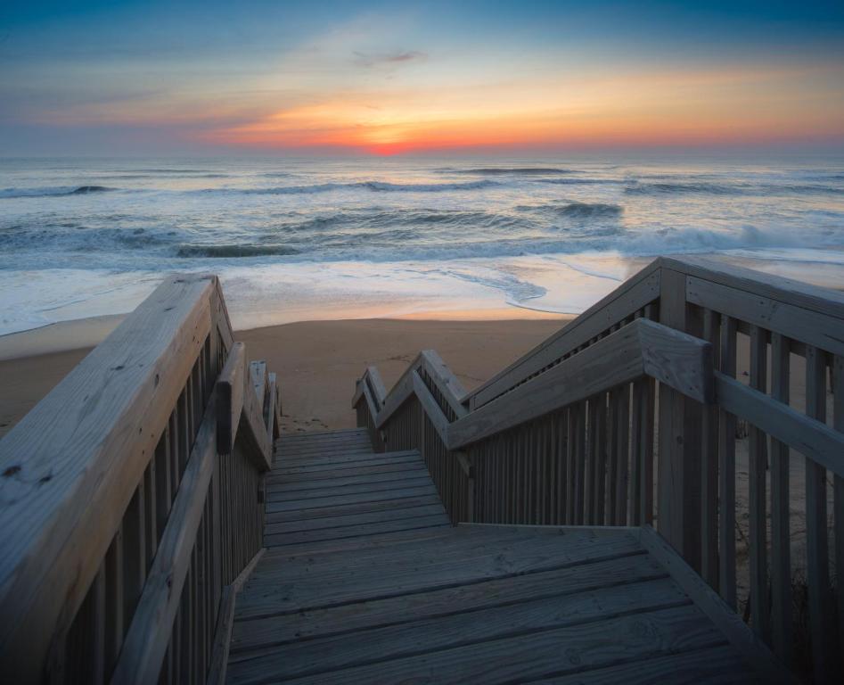 a wooden staircase leading to the beach at sunset at Holiday Inn Express Nags Head Oceanfront, an IHG Hotel in Nags Head