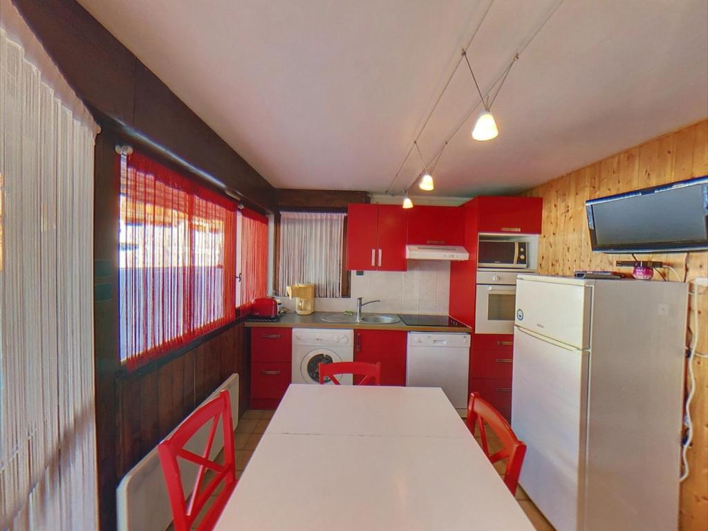 cocina con armarios rojos y nevera blanca en EA115 - 2 Pièces 6 Pers proche centre des Carroz, en Les Carroz d'Araches