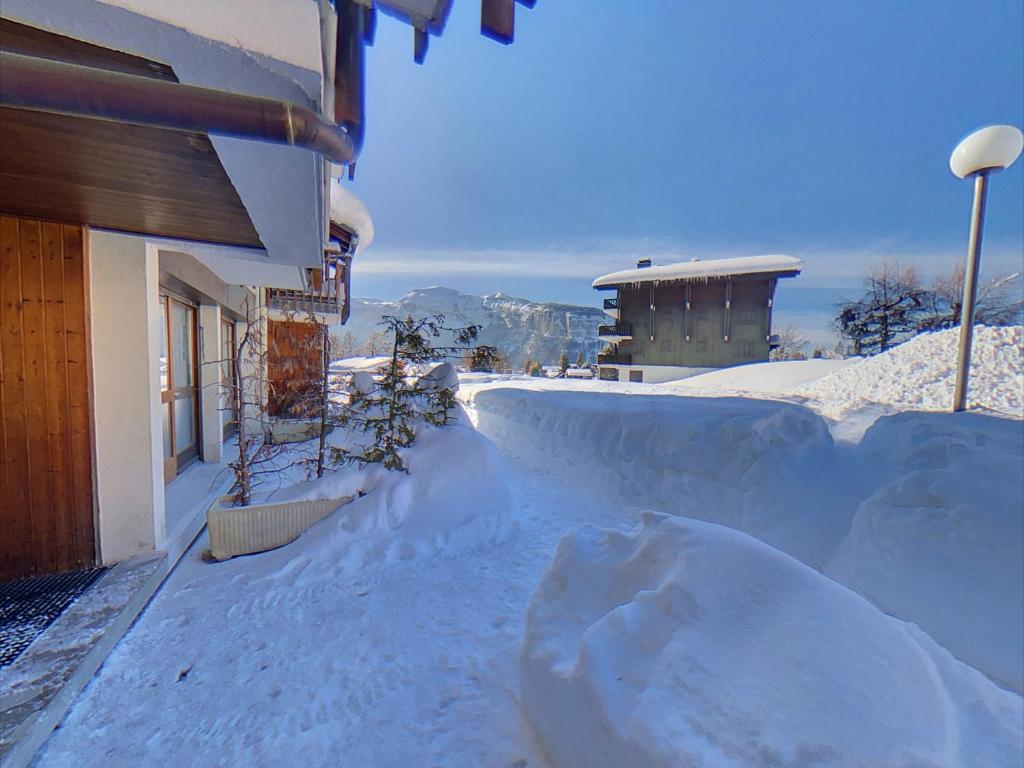 un patio cubierto de nieve junto a un edificio en EA031 - Studette proche centre des Carroz, en Les Carroz d'Araches