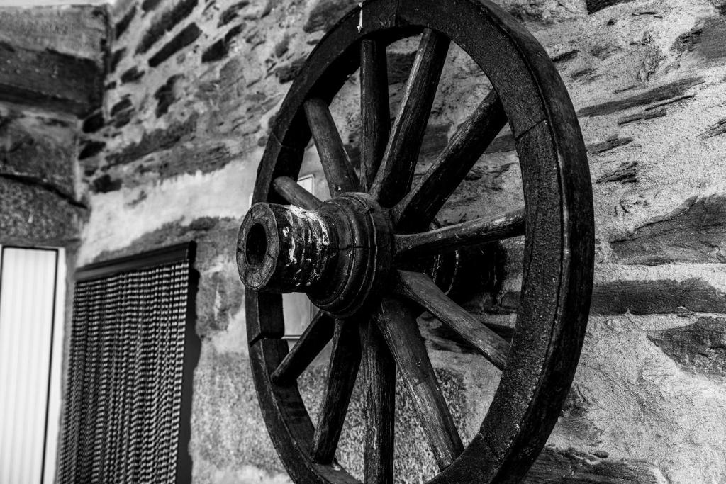 a wooden wagon wheel attached to a stone wall at Casa da Passagem in Vila Real