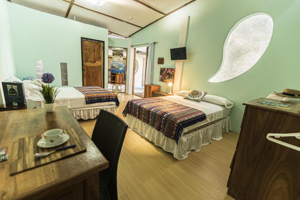 ein Hotelzimmer mit 2 Betten und einem Tisch in der Unterkunft Cozy Hosting Galapagos in Puerto Ayora