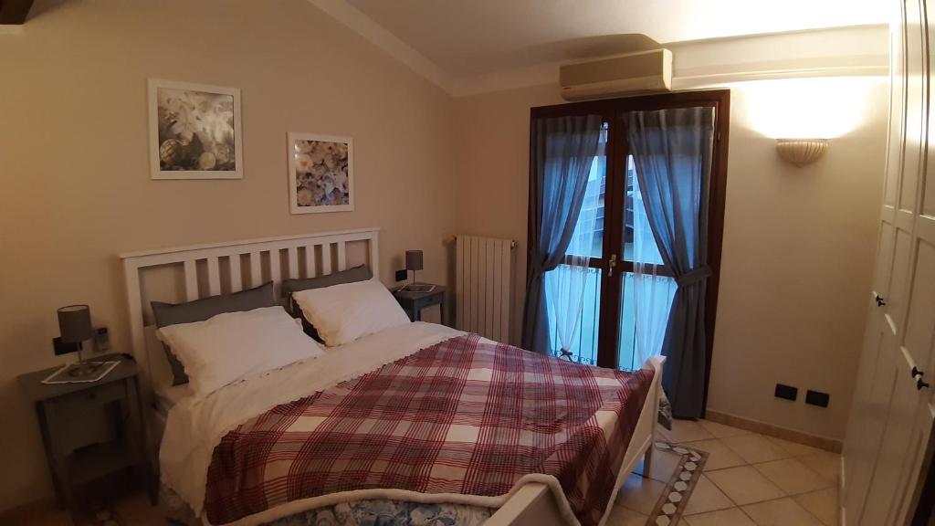 a bedroom with a bed with a plaid blanket and a window at Casa Leuca ALBENGA in Albenga