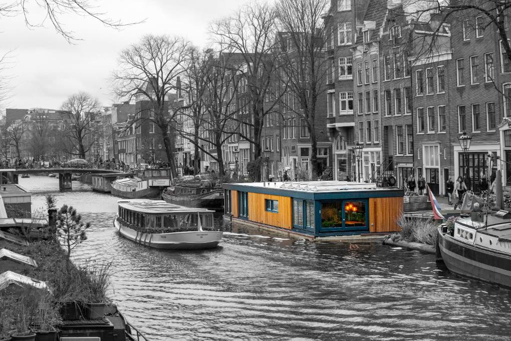 2 Houseboat Suites Amsterdam Prinsengracht في أمستردام: بضع قوارب على نهر مع مباني