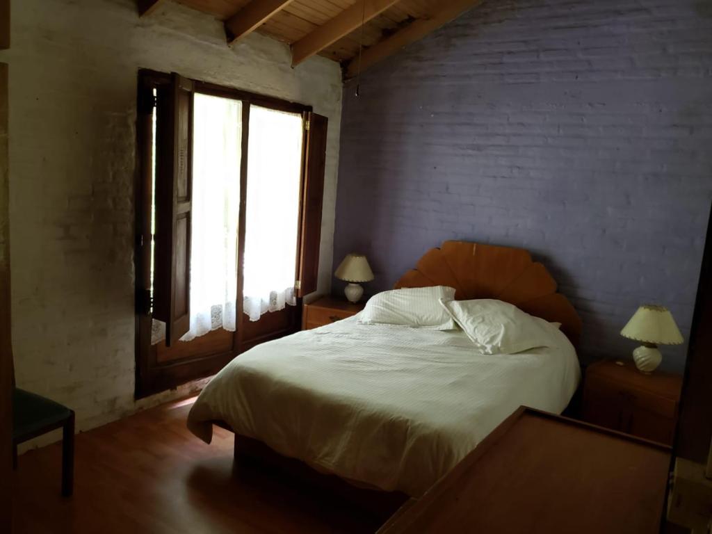 Un dormitorio con una cama blanca y una ventana. en La Casa de Lili, en La Pedrera