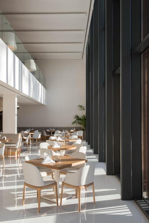 a restaurant with wooden tables and white chairs at Aroeira Lisbon Hotel - Sea & Golf in Aroeira