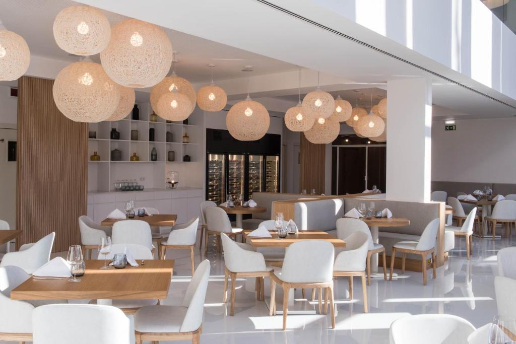 a restaurant with tables and chairs and chandeliers at Aroeira Lisbon Hotel - Sea & Golf in Aroeira