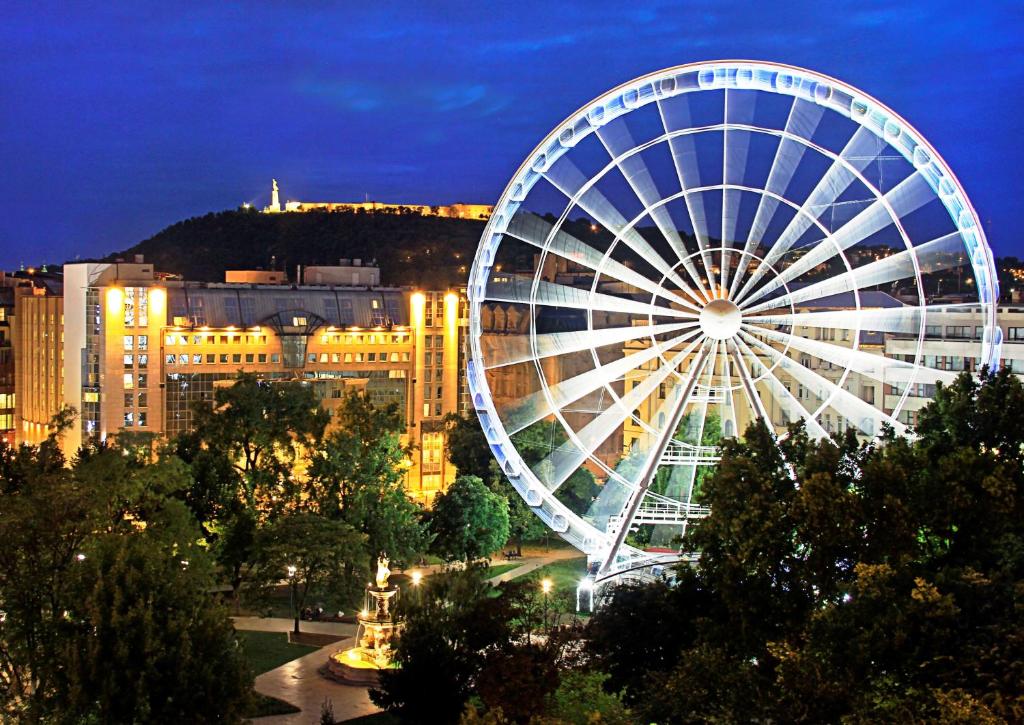 a large ferris wheel in a city at night at Kempinski Hotel Corvinus Budapest in Budapest