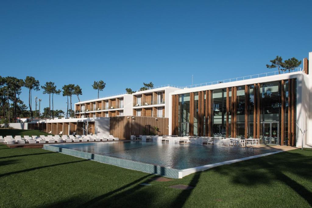 a building with a pool and chairs in front of it at Aroeira Lisbon Hotel - Sea & Golf in Aroeira