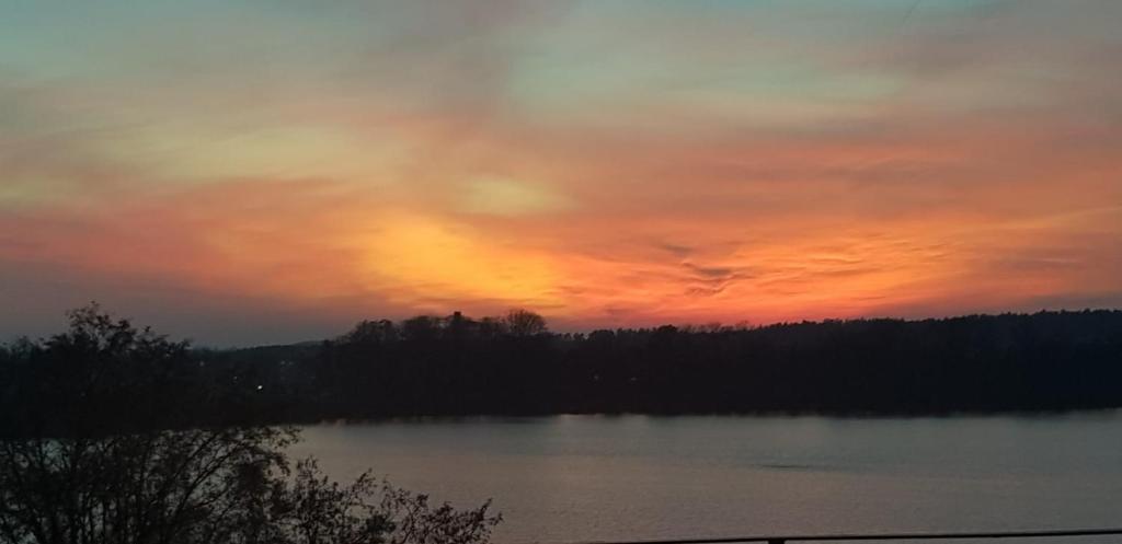 un tramonto su un corpo di acqua con alberi di Apartament Ełk Promenada a Ełk