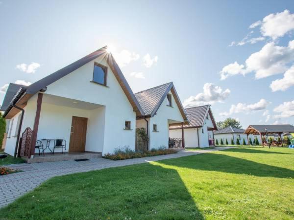a white house with a green lawn in front of it at Domki u Bogdana in Dąbki