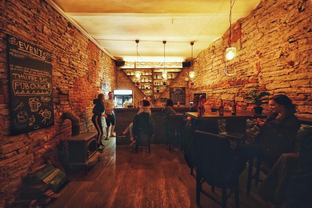 a room with a brick wall and people sitting in a bar at The Monks Bunk Hostel & Bar in Tallinn
