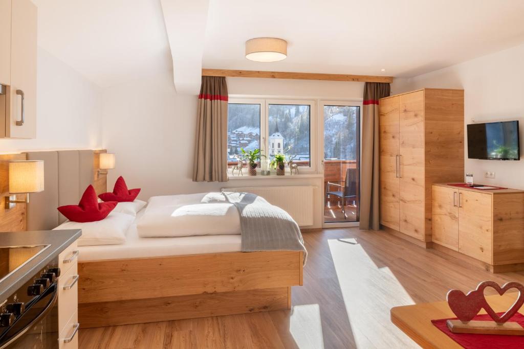 een slaapkamer met een bed en een keuken met een tv bij Appartement Schattauer in Wagrain