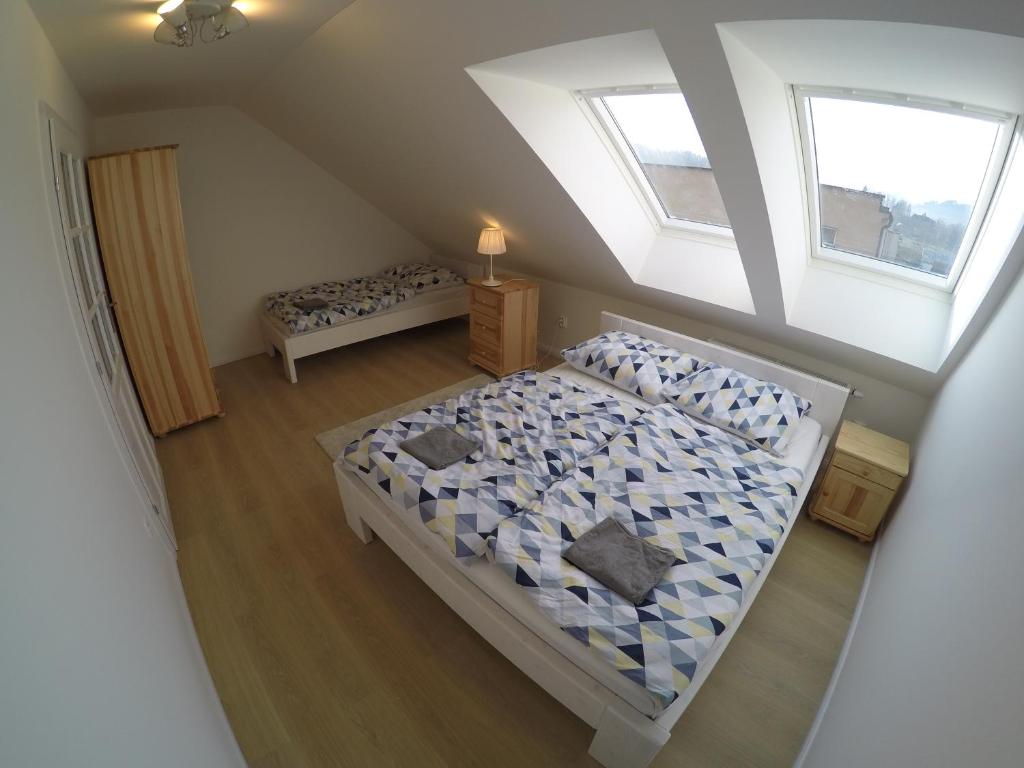 an attic bedroom with two beds and two windows at Apartmány Dúbrava in Dolný Kubín
