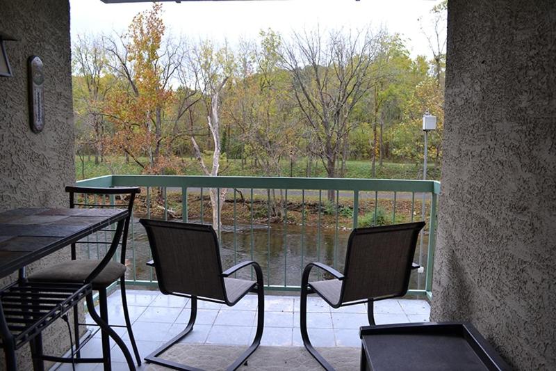 uma varanda com uma mesa e cadeiras e vista para um lago em River Place Condos #407 2BD em Pigeon Forge