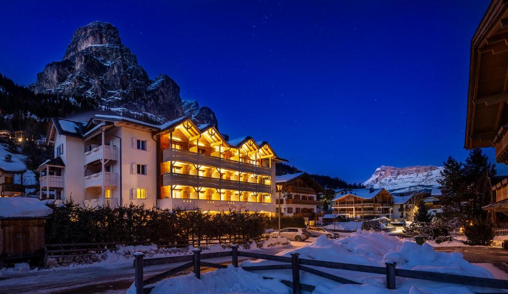 un hotel en la nieve por la noche con una montaña en Hotel Gran Fanes, en Corvara in Badia