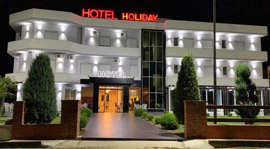 un edificio con un cartello hotel di notte di Hotel Holiday a Koplik