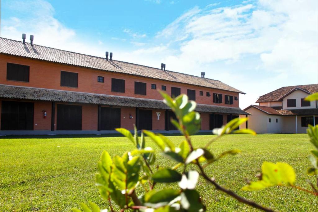 a building with a grass field in front of it at Pousada ACM Tramandaí - RS in Tramandaí