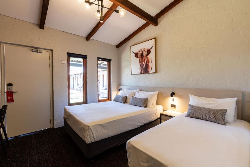 2 Betten in einem Zimmer mit 2 Fenstern in der Unterkunft Nightcap at Wintersun Hotel in Geraldton