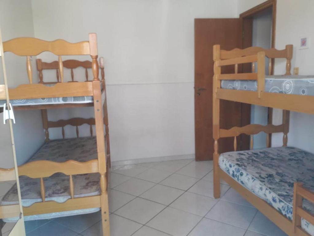 a room with two bunk beds and a bed at Apto PROX PRAIA 2 VAGAS GARAGEM, CHURRASQUEIRA SACADA, 3 DORM-GUILHERMINA in Praia Grande