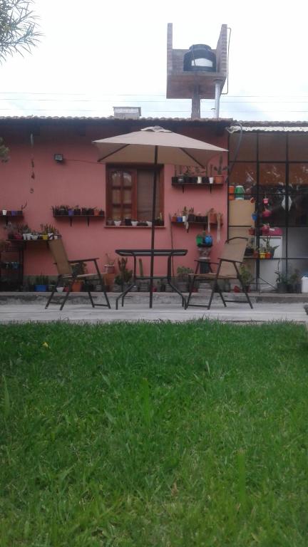 a pink building with a table and an umbrella at La casita de abu! in Salta