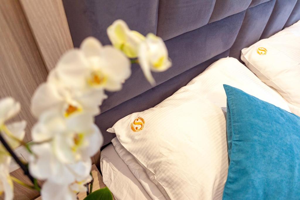 1 cama con almohadas blancas y cabecero azul en Apartmani Stanišić-Bečići, en Bečići