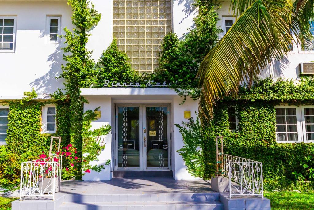 un bâtiment blanc avec une porte et des plantes dans l'établissement Travelodge by Wyndham Miami Biscayne Bay, à Miami