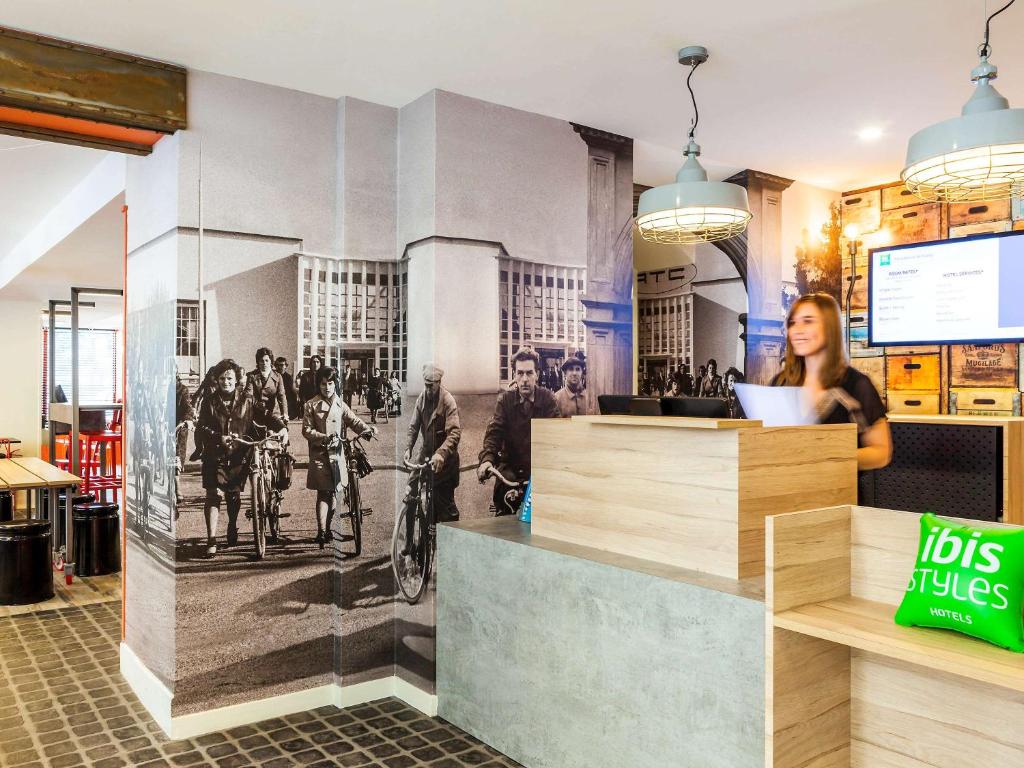 Eine Frau, die hinter einem Tresen in einem Restaurant steht. in der Unterkunft ibis Styles Paris Mairie De Clichy in Clichy