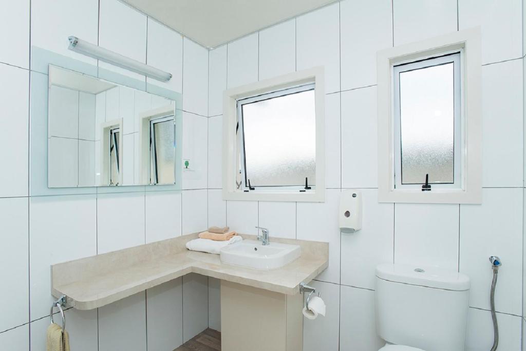 a white bathroom with a sink and a toilet at AhiKaa Gisborne Motel in Gisborne