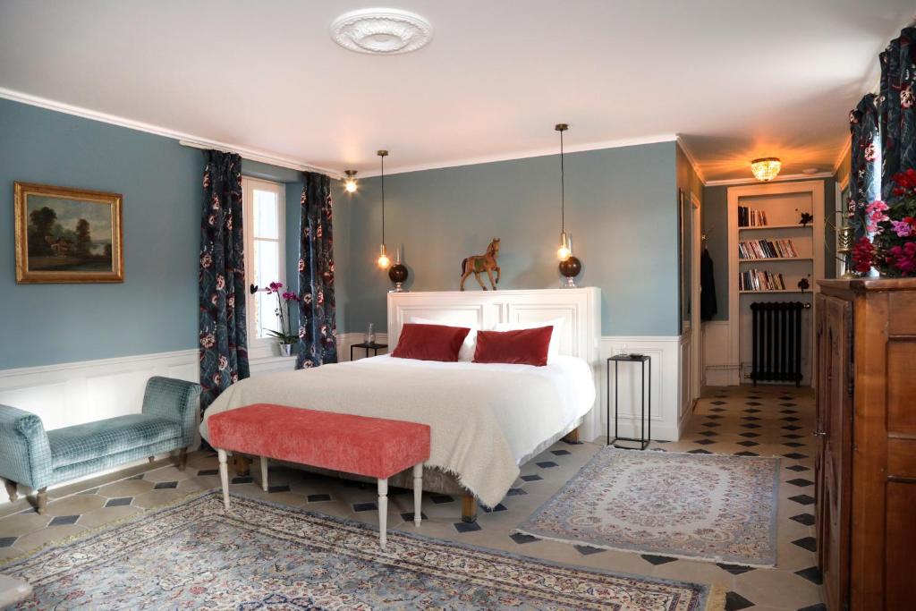 a bedroom with a white bed and a red chair at Domaine du Plessis in Le Plessis-Luzarches