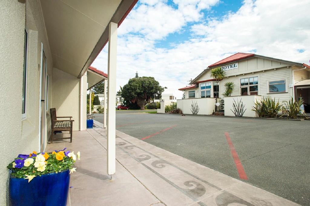 a building with a porch with flowers in a pot at AhiKaa Gisborne Motel in Gisborne