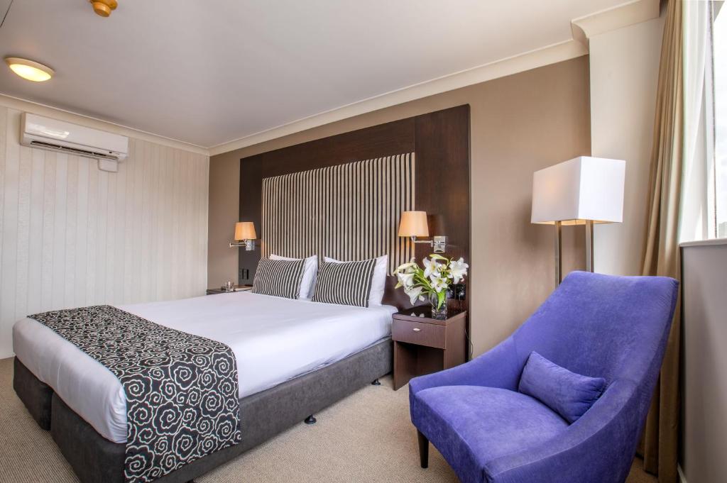 una camera d'albergo con letto e sedia blu di Mercure Wellington Abel Tasman Hotel a Wellington