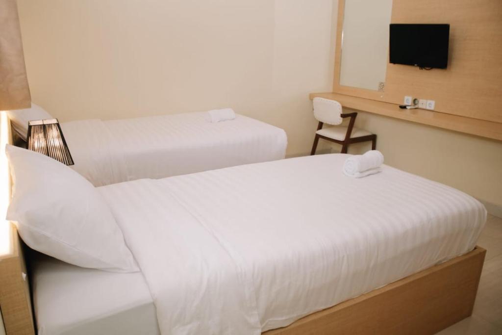 a hotel room with two beds and a television at Merlin Hotel in Maumere
