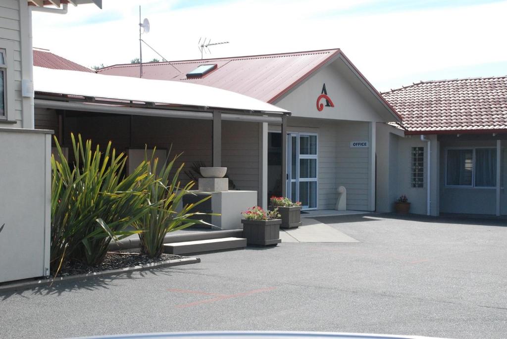 a house with a garage with plants in front of it at AhiKaa Gisborne Motel in Gisborne