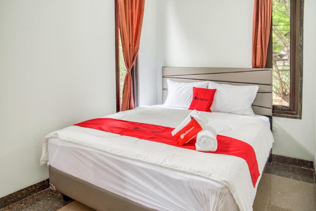 a bed with two red pillows and a red blanket at RedDoorz near Taman Mini Jakarta in Jakarta