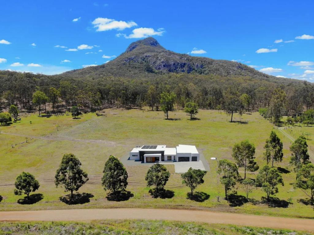 a house in a field with a mountain in the background at Elysium Fields Moogerah in Moogerah