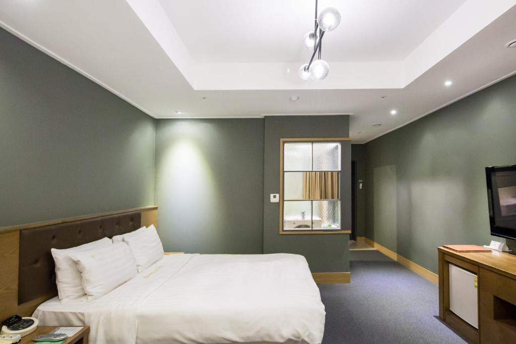 1 dormitorio con 1 cama grande y TV en The Koryo Hotel en Bucheon