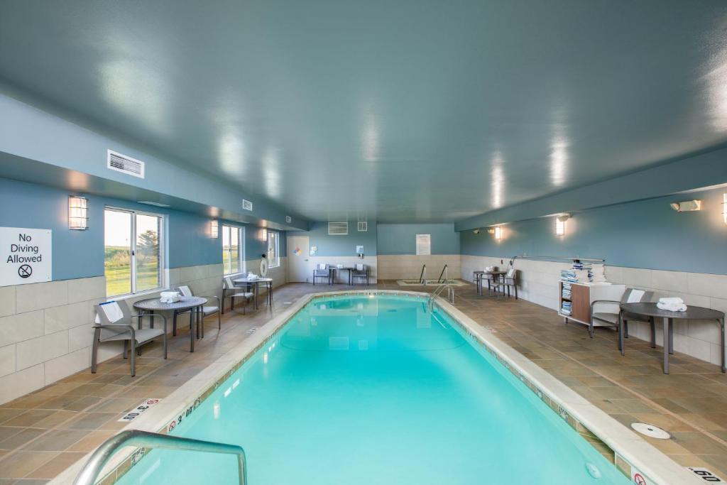 a swimming pool with tables and chairs in a building at Holiday Inn Express Hotel & Suites Altoona-Des Moines, an IHG Hotel in Altoona