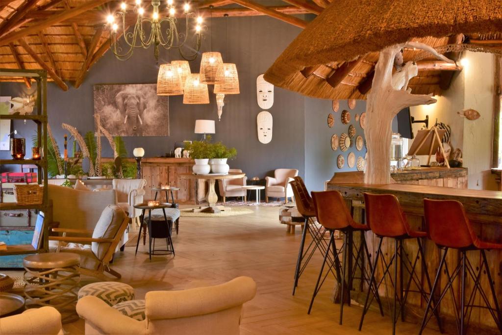 un bar en una habitación con sillas y mesas en Bayala Private Safari Lodges, en Hluhluwe