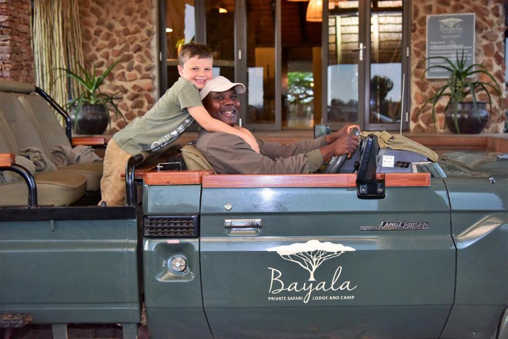a man and a child riding in the back of a truck at Bayala Private Safari Lodges in Hluhluwe