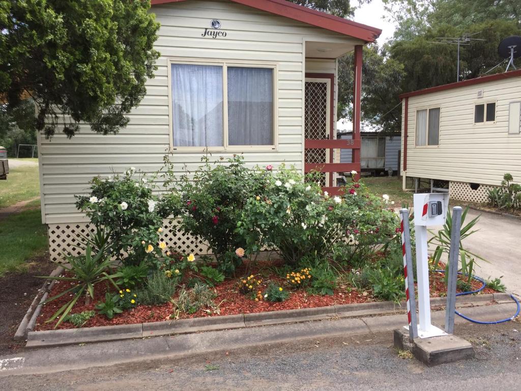 a garden in front of a house with flowers at Caracourt caravan park in Singleton