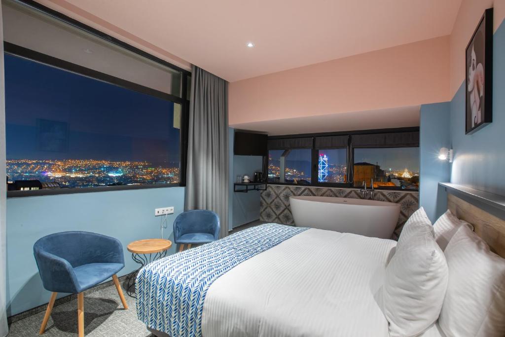 a hotel room with a bed and a large window at Vera Hills Boutique Hotel in Tbilisi City