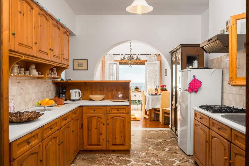 a kitchen with wooden cabinets and a white refrigerator at Katoussa in Paleokastritsa