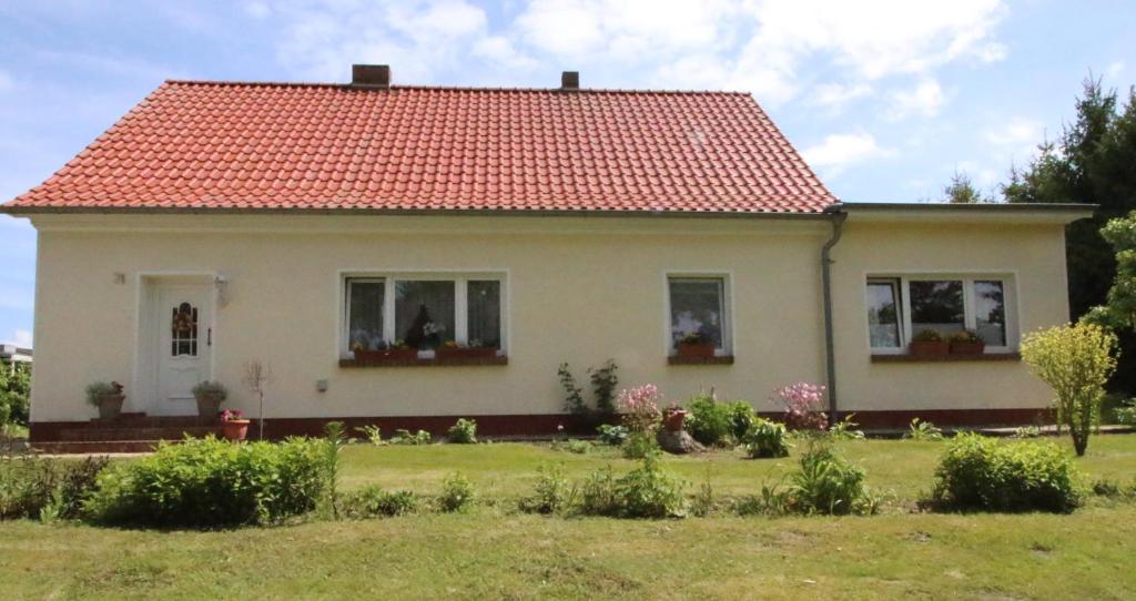 a small white house with a red roof at Ferienwohnung An den Tannen in Bartelshagen