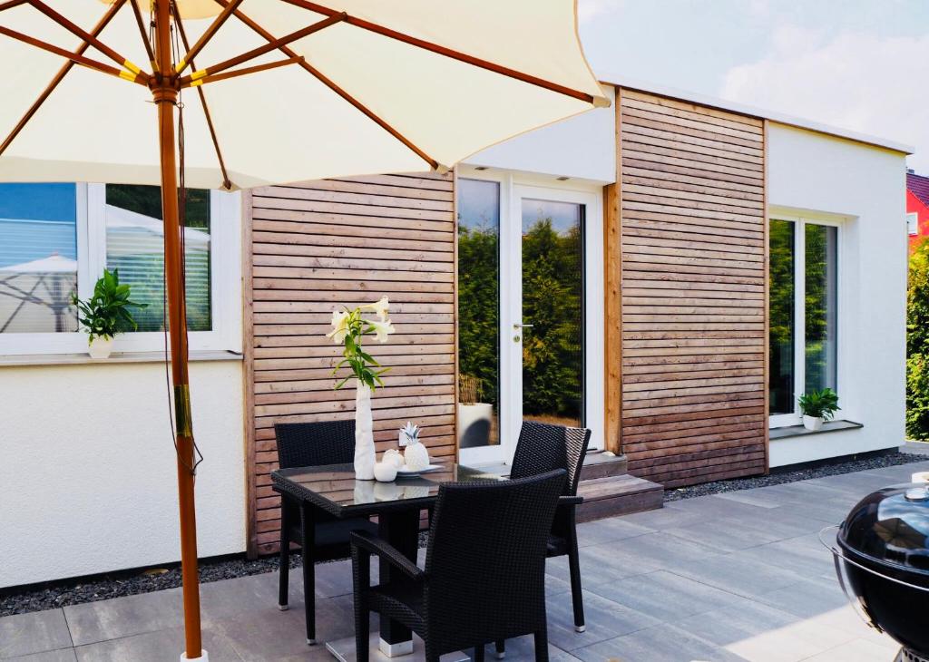 a table with chairs and an umbrella on a patio at CasaSmart // Das Ferienhaus am Harz Nordhausen in Nordhausen