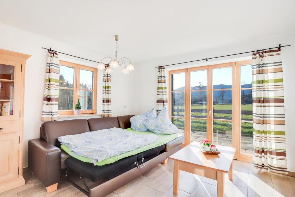 a bed in a room with a couch and windows at Ferienwohnung Bergblick in Bad Heilbrunn