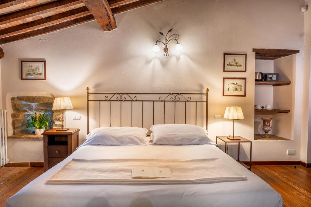una camera da letto con un grande letto bianco con due lampade di Castello Di Petrata ad Assisi