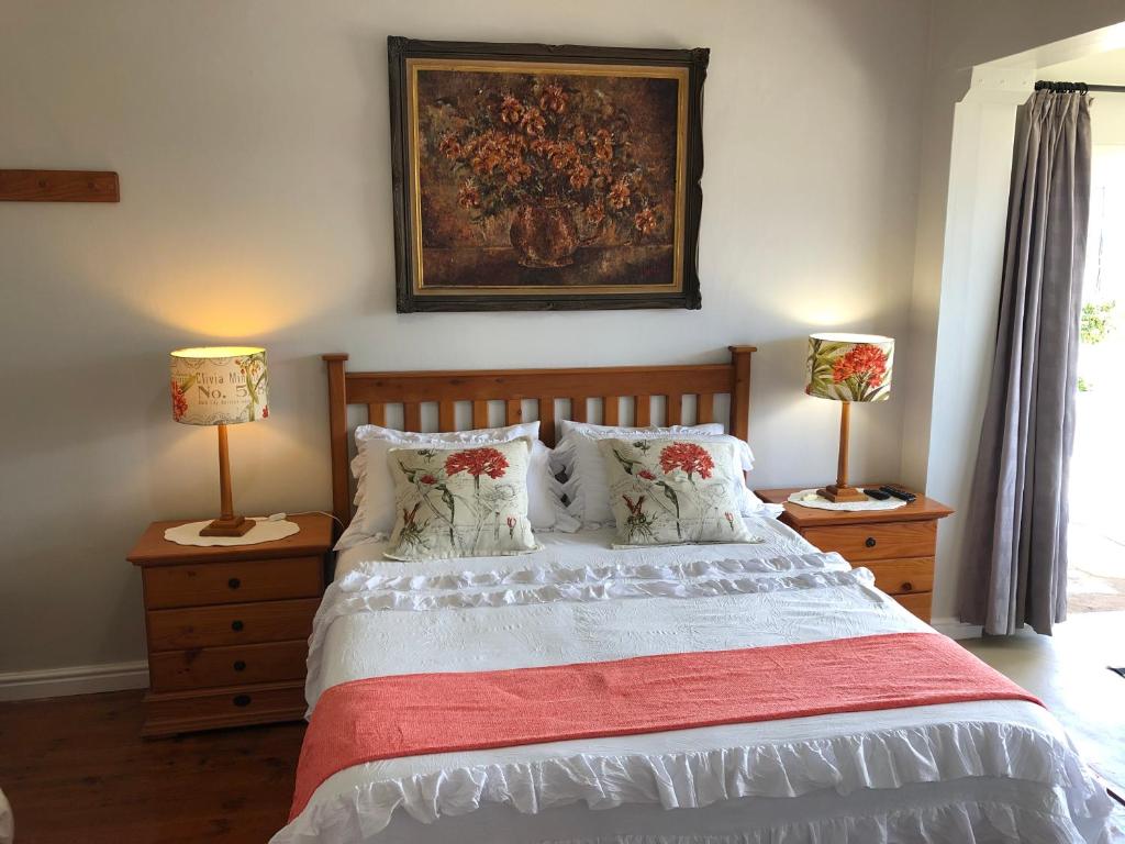 a bedroom with a bed with two lamps and a painting on the wall at Baylight Accomodation in Mossel Bay