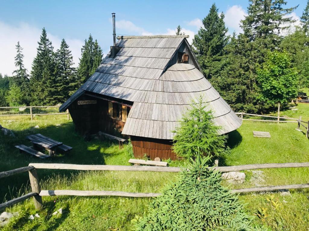 a barn with a tin roof in a field at Chalet Gasparjeva Velika Planina in Kamnik