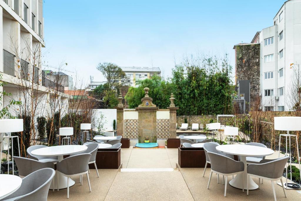 un patio con mesas, sillas y una fuente. en Catalonia Porto, en Oporto